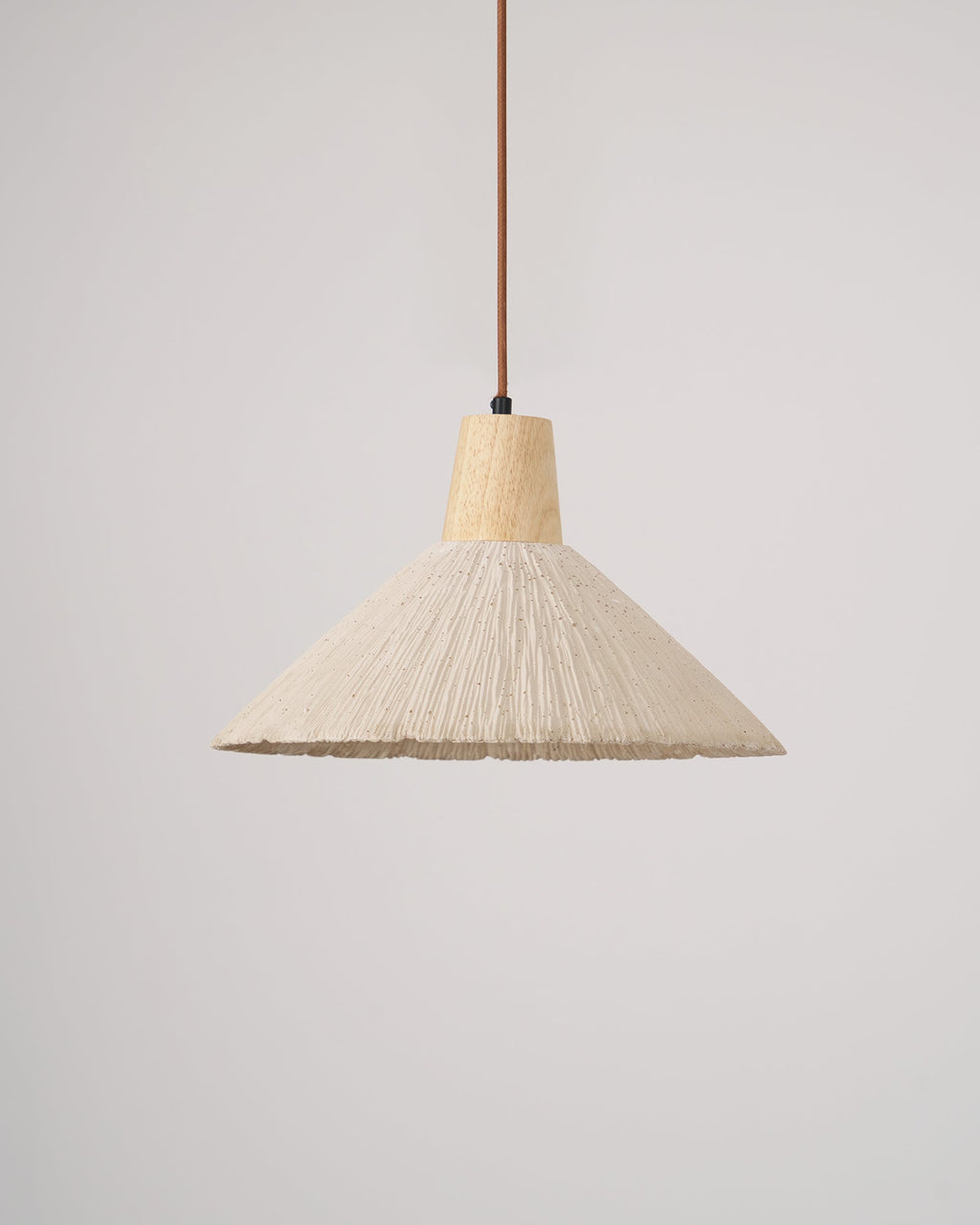 A cream-toned wide-shade Clérachic pendant, unlit, with a wooden cap and brown cord against a plain light grey backdrop.