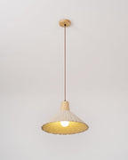 A cream-toned Clérachic pendant on a wooden canopy, lit warm, with its bulb and pleated rim against a plain backdrop.