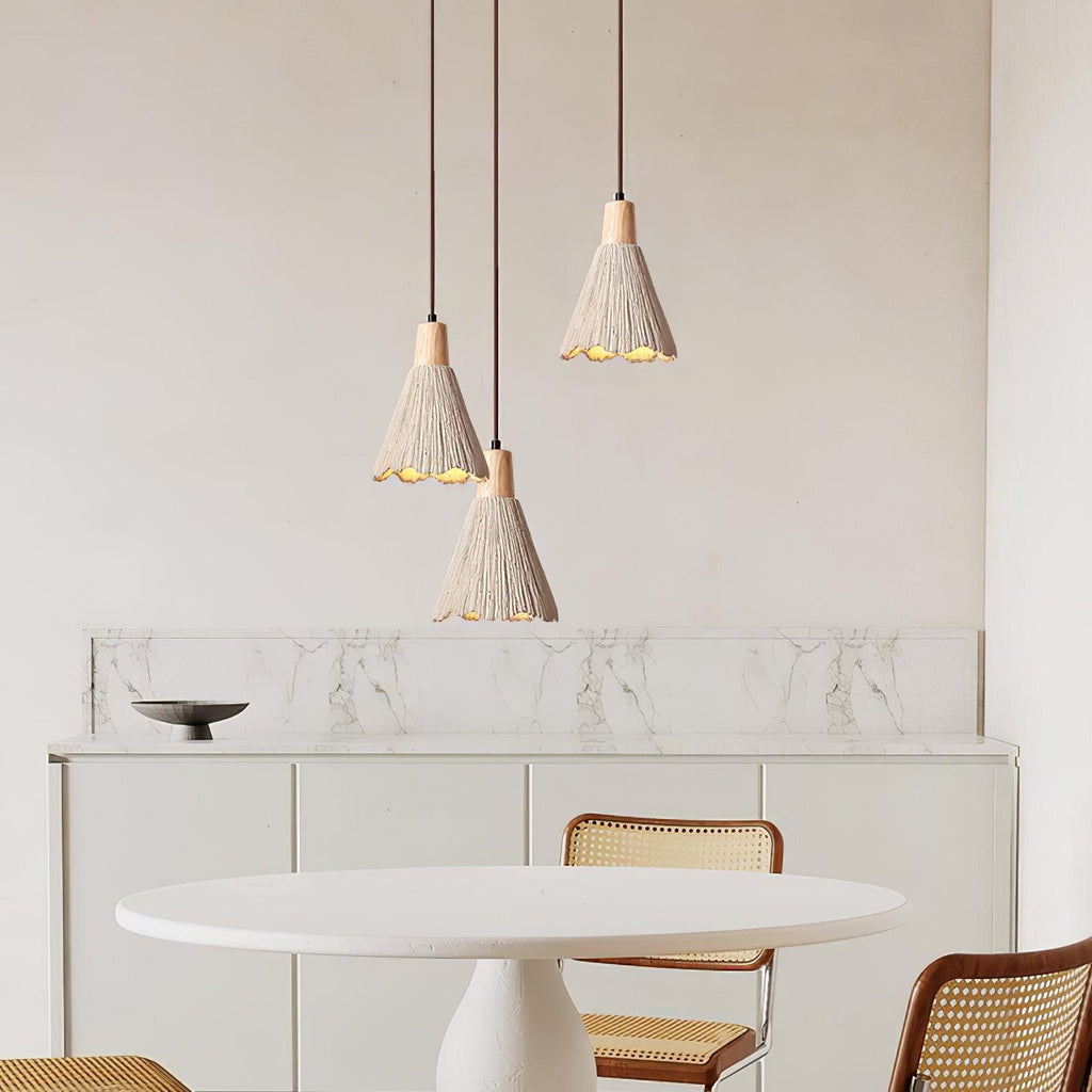 Three Clérachic pendants hang at different heights over a round white table, with a marble-topped sideboard behind.