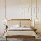 Two Clérachic pendants flank a bed with a rattan headboard and a carved white wall panel behind it.