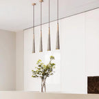 A row of four slim Clérachic pendants hangs against a white wardrobe wall, with a leafy plant in a glass vase below.