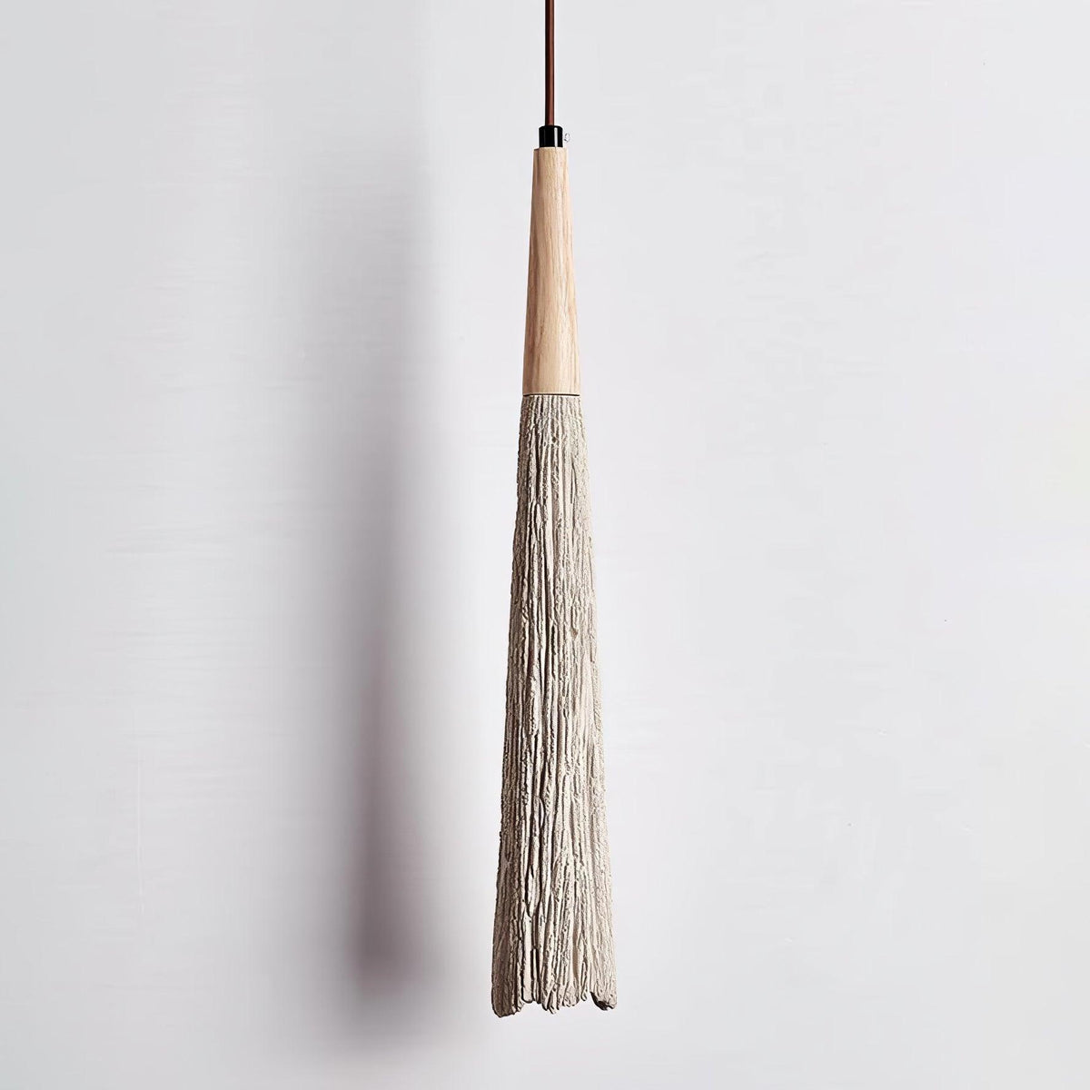 The textured, bark-like surface of this slim Clérachic pendant, seen close up with its wooden collar and black fitting.