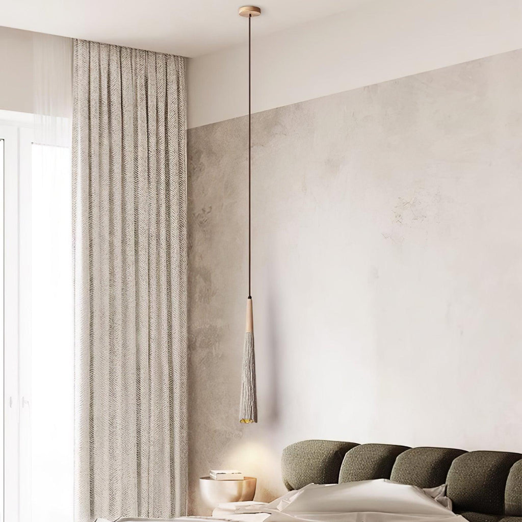 A single slim Clérachic pendant on a wooden ceiling rose hangs beside a long curtain and a dark-green sofa.