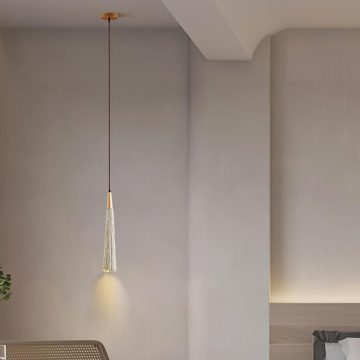 A single slim Clérachic pendant with a wooden canopy glows in a bedroom corner with soft cove lighting behind.