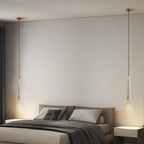 A slim Clérachic pendant hangs on each side of a made bed in a calm grey bedroom.