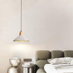 A single wide-cone Clérachic pendant hangs by a sage-green sofa and sculptural metallic side tables.