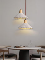 A pair of Clérachic pendants with wide cone shades light a round white dining table with grey chairs.