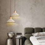 Two wide Clérachic pendants hang at different heights against a textured plaster wall, beside an olive-green sofa.