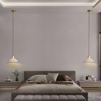 A wide-shade Clérachic pendant hangs on each side of a bed with a grey headboard and a wide bench.