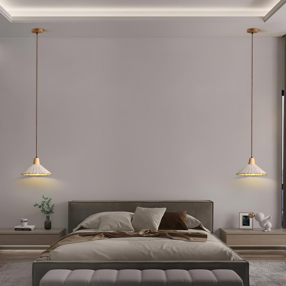 A wide-shade Clérachic pendant hangs on each side of a bed with a grey headboard and a wide bench.