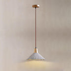 A single Clérachic pendant on a round wooden canopy glows against a beige wall, its grey shade lit from within.