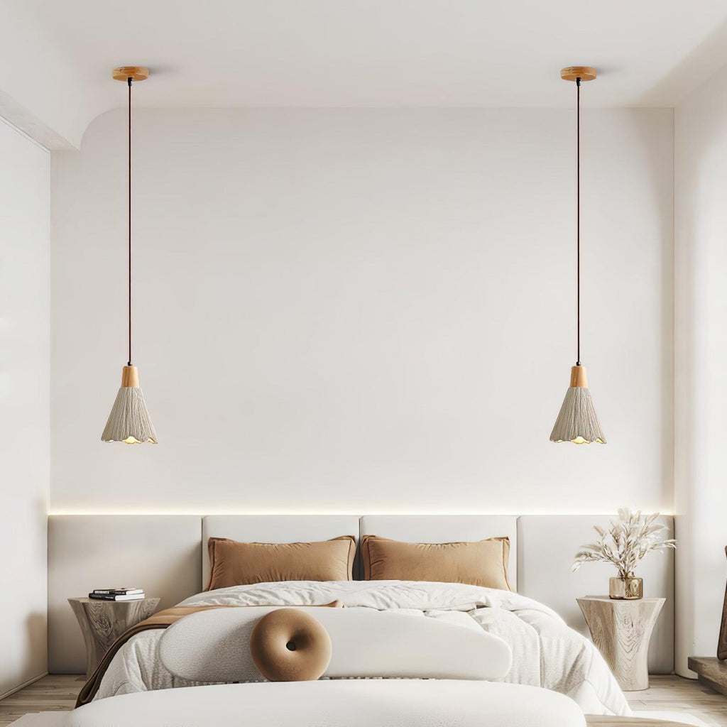 A pair of bell-shaped Clérachic pendants hang on wooden canopies above a bed with tan cushions.