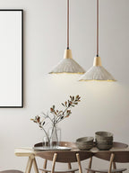 Two wide-shade Clérachic pendants glow above a dining table set with stacked bowls and a vase of branches.