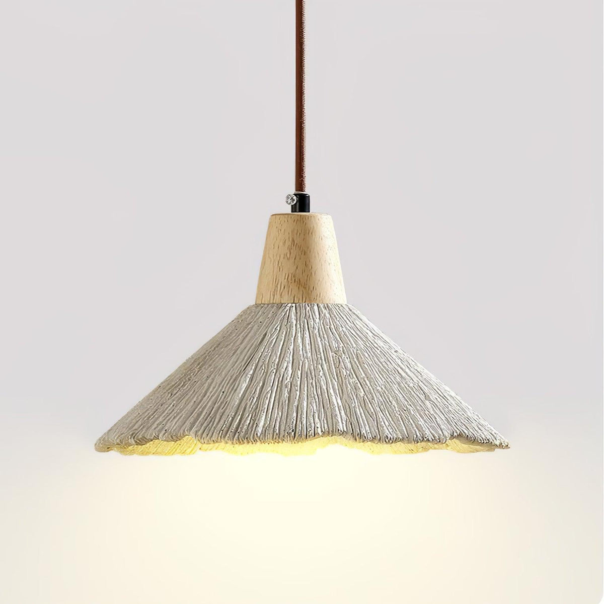 Close view of this Clérachic pendant from below, its wide grey shade lit warmly beneath a wooden cap and a braided cord.