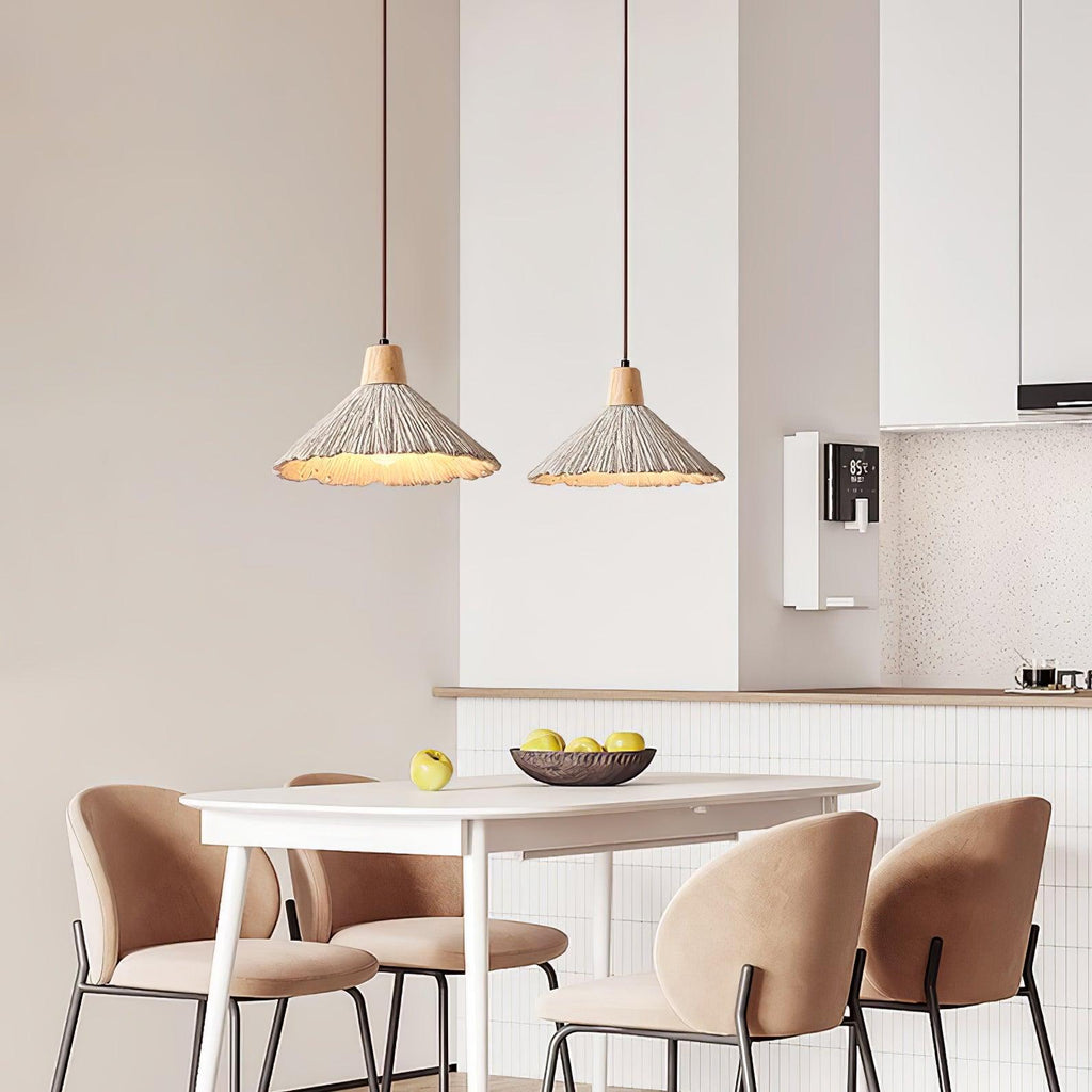 Two wide-shade Clérachic pendants hang over a white dining table with blush chairs and a bowl of lemons in a small kitchen.