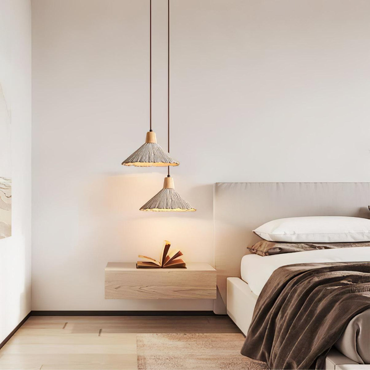 Two bell-shaped Clérachic pendants hang at staggered heights over a floating shelf with an open book, beside a bed.