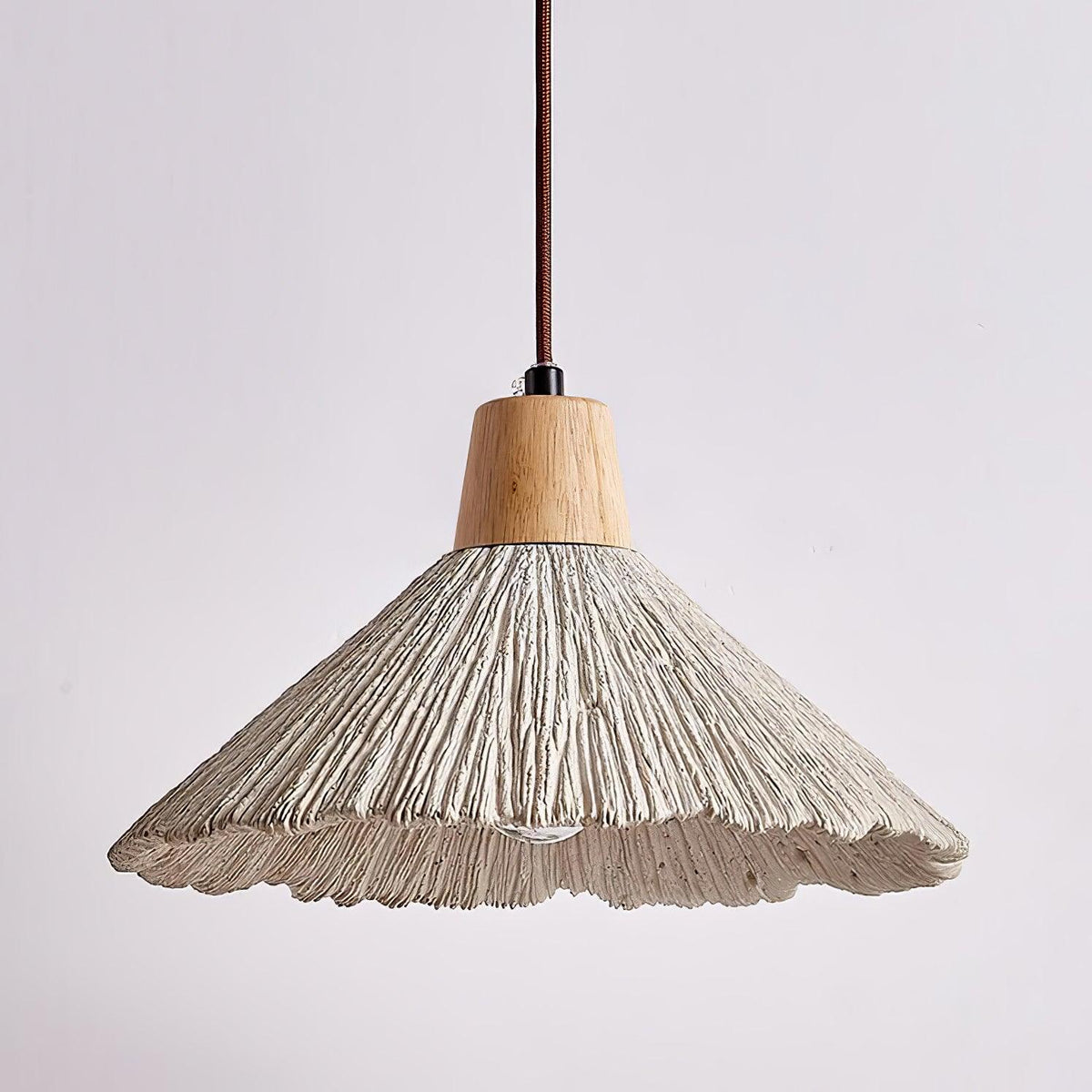 A wide Clérachic pendant seen from slightly below, its scalloped grey rim and ridged shade clear against a soft background.