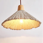 Seen from underneath, this Clérachic pendant's shade glows warm around a visible bulb, with a wooden cap and brown cord above.