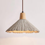 Lit wide-shade Clérachic pendant with a ridged grey surface, a wooden cap and a glowing warm underside.