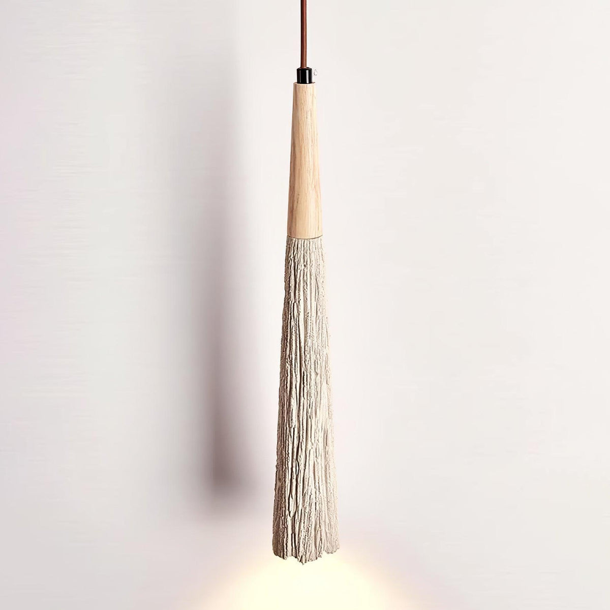 Close view of a long, narrow Clérachic pendant with a wooden top and a ridged grey tapered shade, lit at the tip.