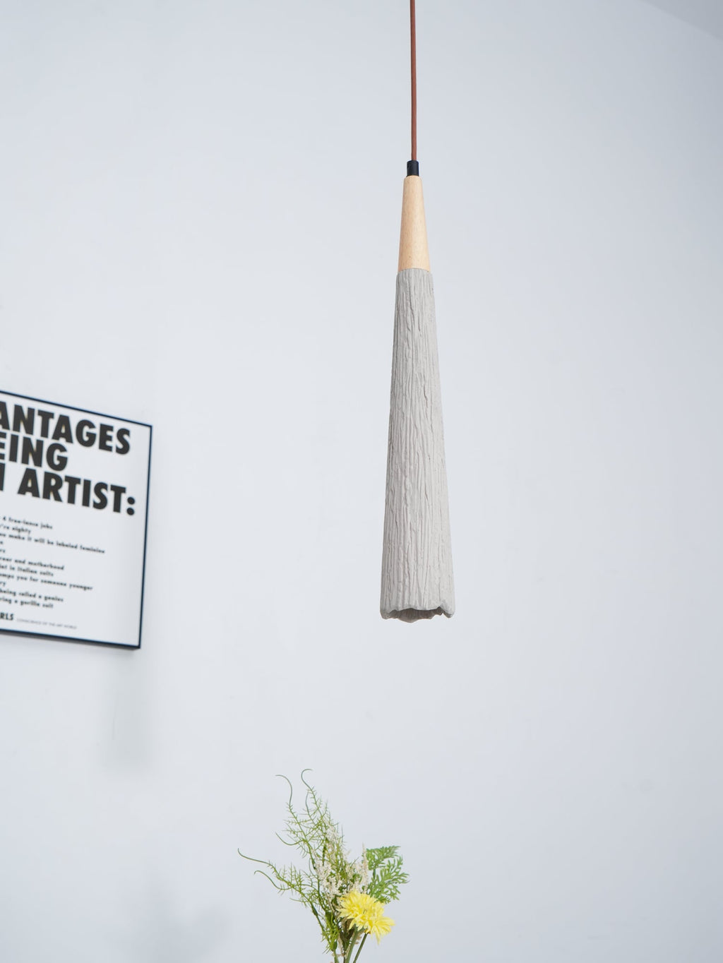 Slim Clérachic pendant with a ridged grey tapered shade and a wooden collar, with part of a framed print beside it.