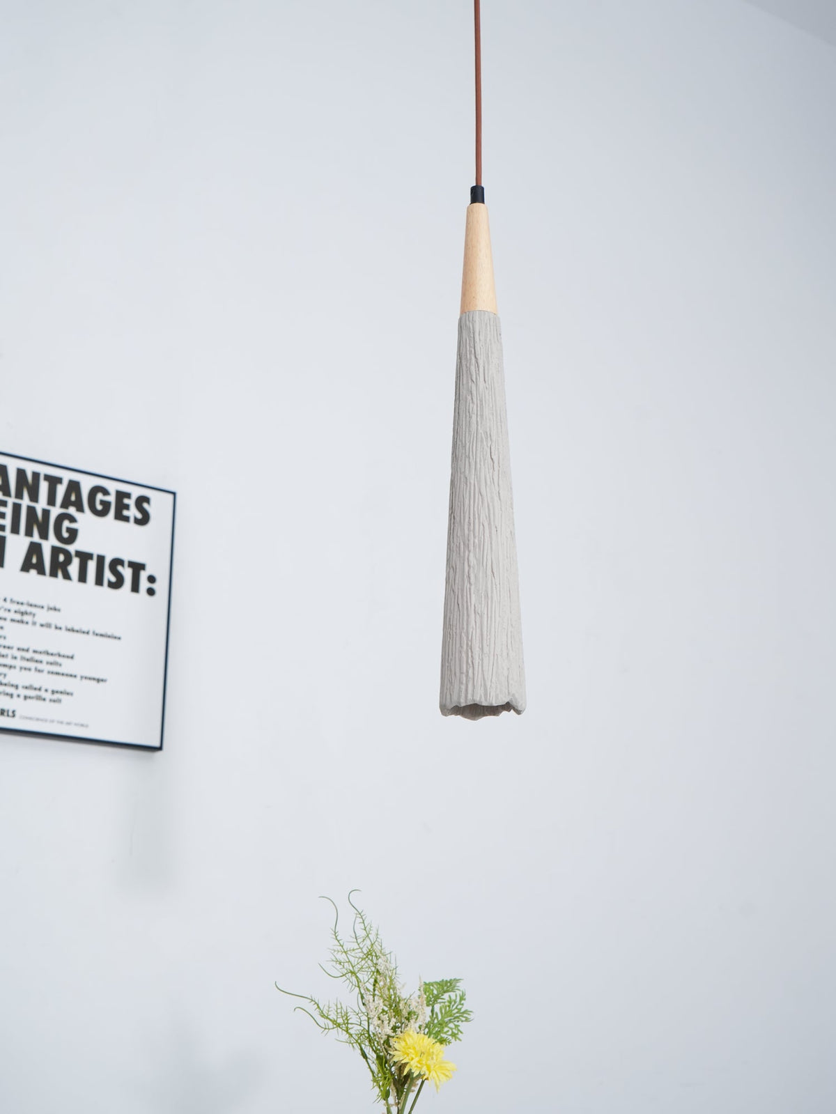 Slim Clérachic pendant with a ridged grey tapered shade and a wooden collar, with part of a framed print beside it.