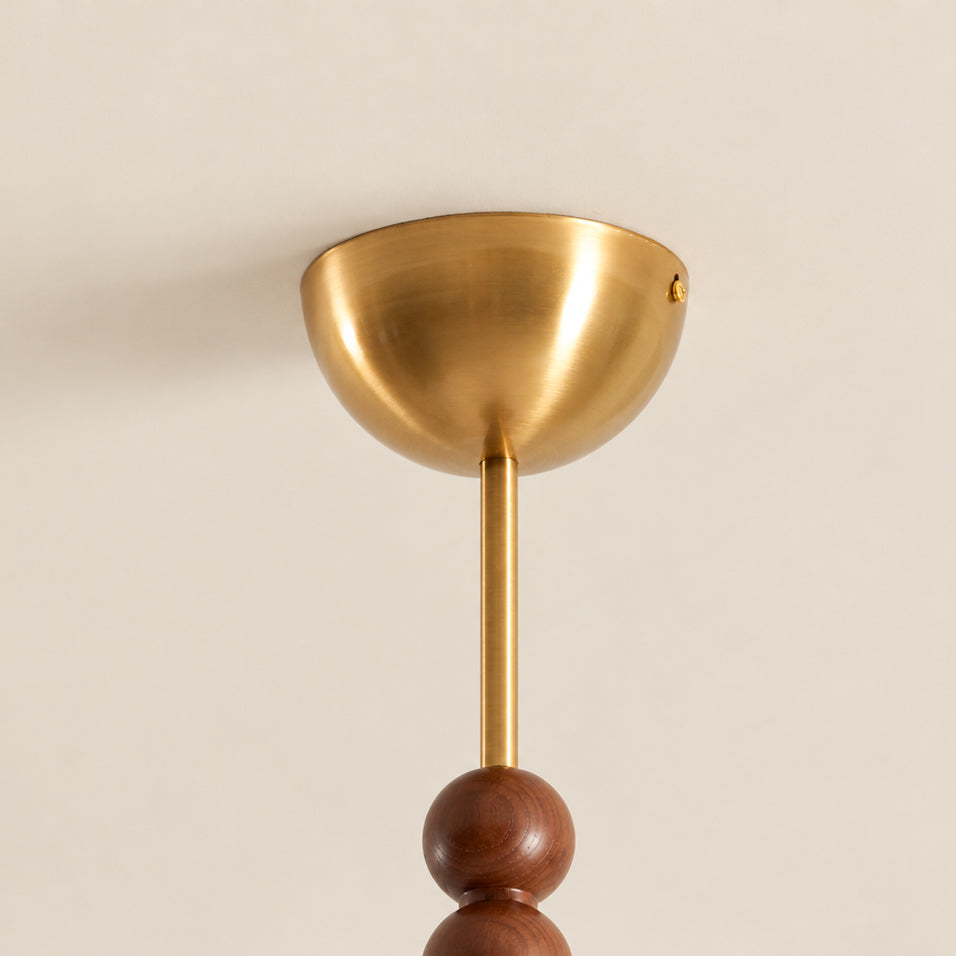 Close view of the brass dome canopy and thin brass stem above a walnut bead on this Clérachic ceiling light.