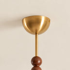 Close view of the brass dome canopy and thin brass stem above a walnut bead on this Clérachic ceiling light.