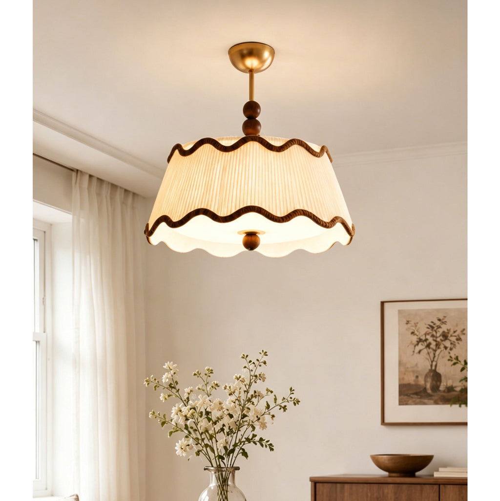 Lit Clérachic pleated ceiling light with wavy brown trim in a bedroom, with a vase of white flowers and sheer curtains.