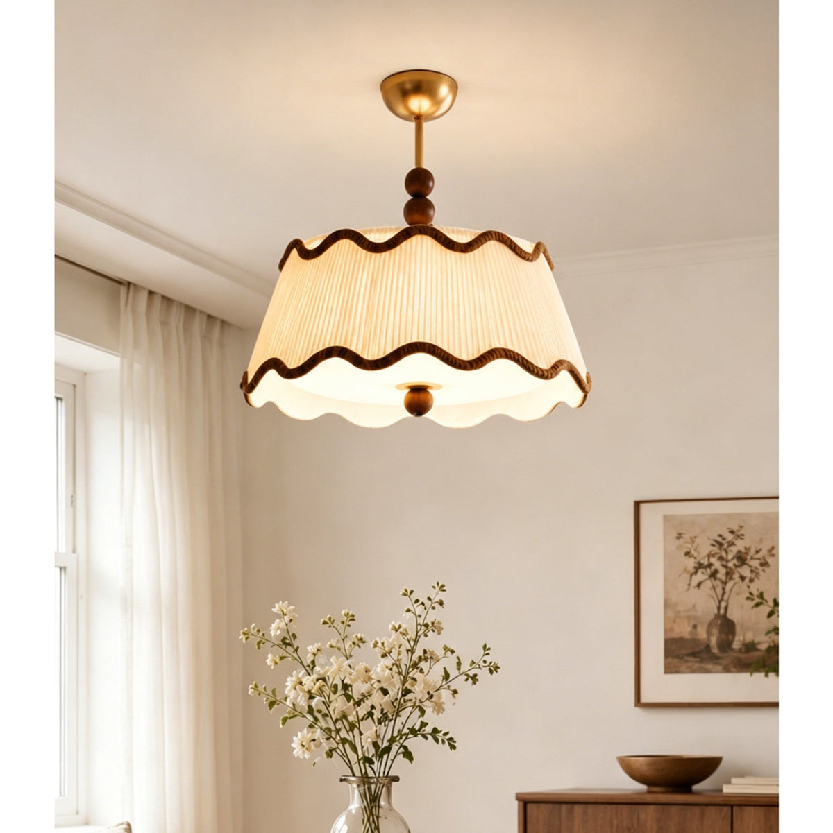 Lit Clérachic pleated ceiling light with wavy brown trim in a bedroom, with a vase of white flowers and sheer curtains.