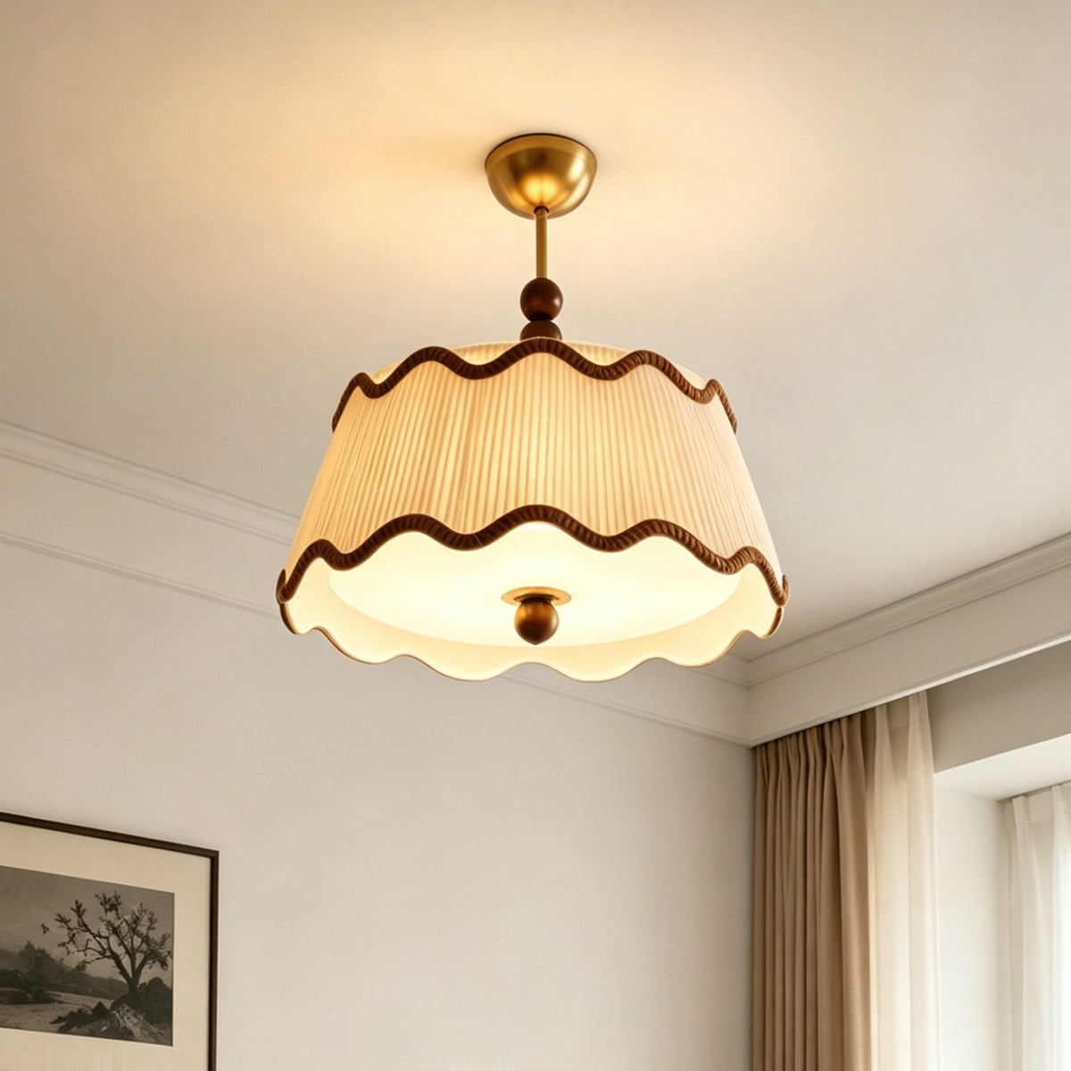 Angled view from below at the lit diffuser and scalloped hem of a Clérachic ceiling light, with a framed print and curtains beside it.
