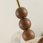 Angled close view of the walnut bead stack and brass stem on this Clérachic ceiling light, showing the wood grain.