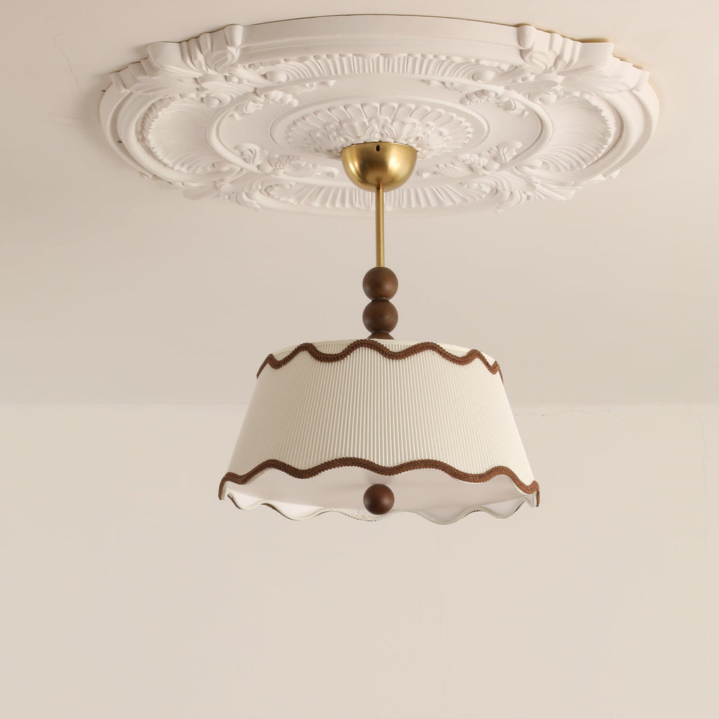 Unlit white Clérachic ceiling light with wavy brown trim beneath a carved plaster ceiling rose, from a low angle.