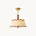 Lit Clérachic pleated ceiling light in warm cream with wavy brown trim and a brass canopy, on a plain white backdrop.
