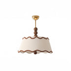 Unlit white pleated Clérachic ceiling light with wavy brown trim, walnut beads and a small brass canopy, on a white backdrop.