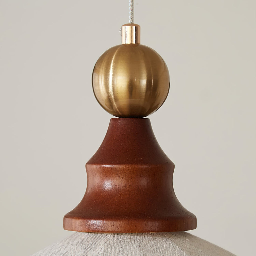 Close view of the brass ball and carved walnut cap at the top of this Clérachic pendant light.