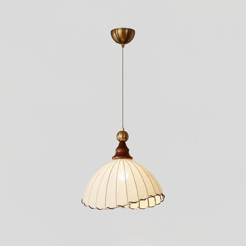 Beige Clérachic pendant light with a brass canopy and thin cord, lit against a pale grey backdrop.