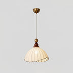 Beige Clérachic pendant light with a brass canopy and thin cord, lit against a pale grey backdrop.