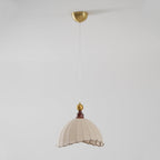 This Clérachic pendant light hangs far below its brass ceiling canopy on a long fine cord, on a pale grey backdrop.