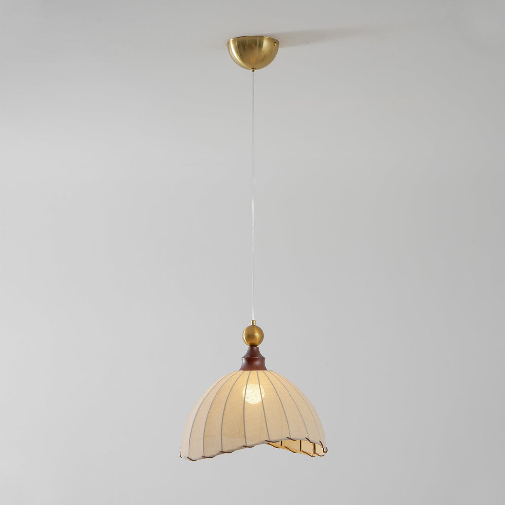 A Clérachic pendant light from below, with the brass canopy at the top and the shade glowing on a grey backdrop.