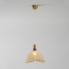 A Clérachic pendant light from below, with the brass canopy at the top and the shade glowing on a grey backdrop.