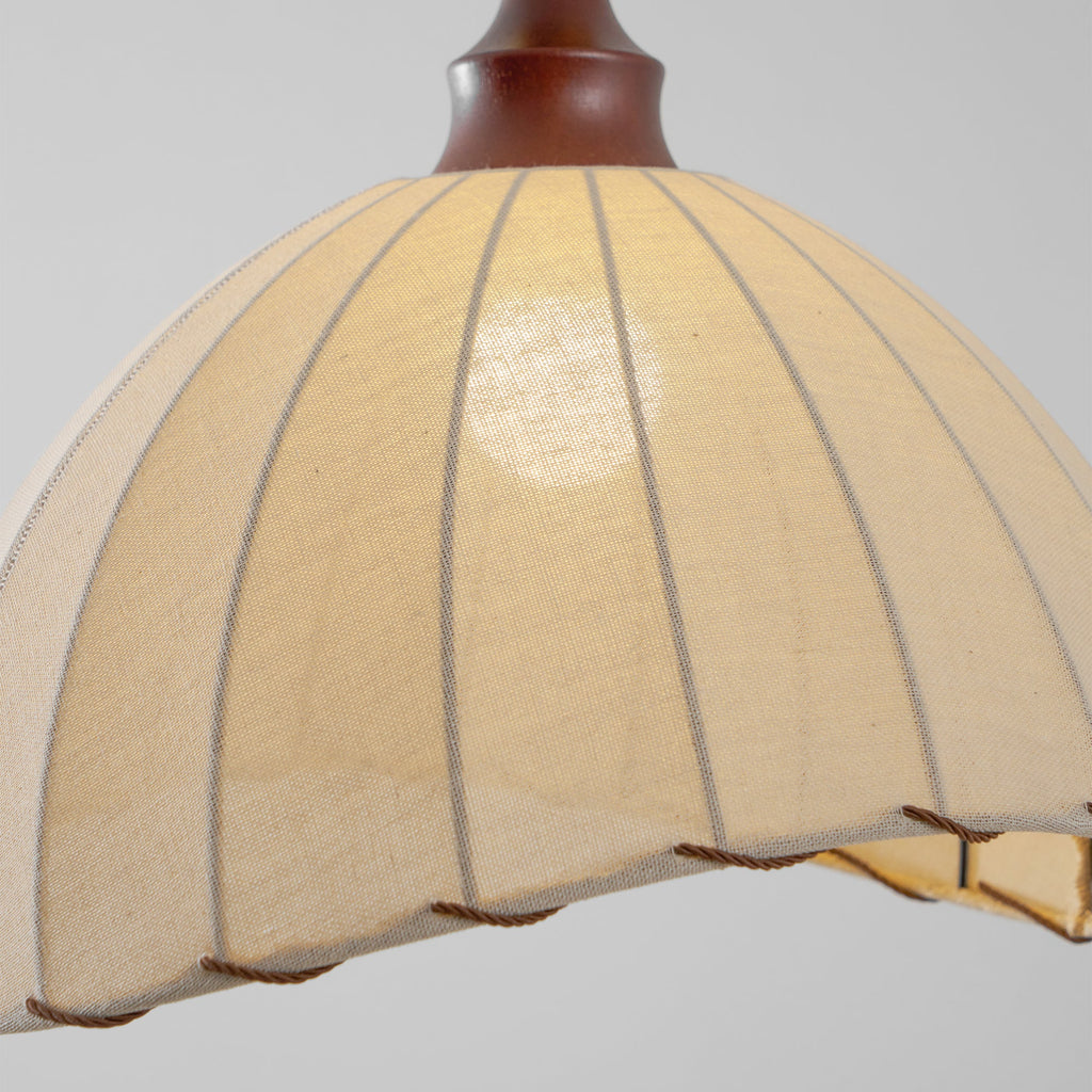 Close view of the inside glow and ribbed seams of the beige fabric shade on this Clérachic pendant light.