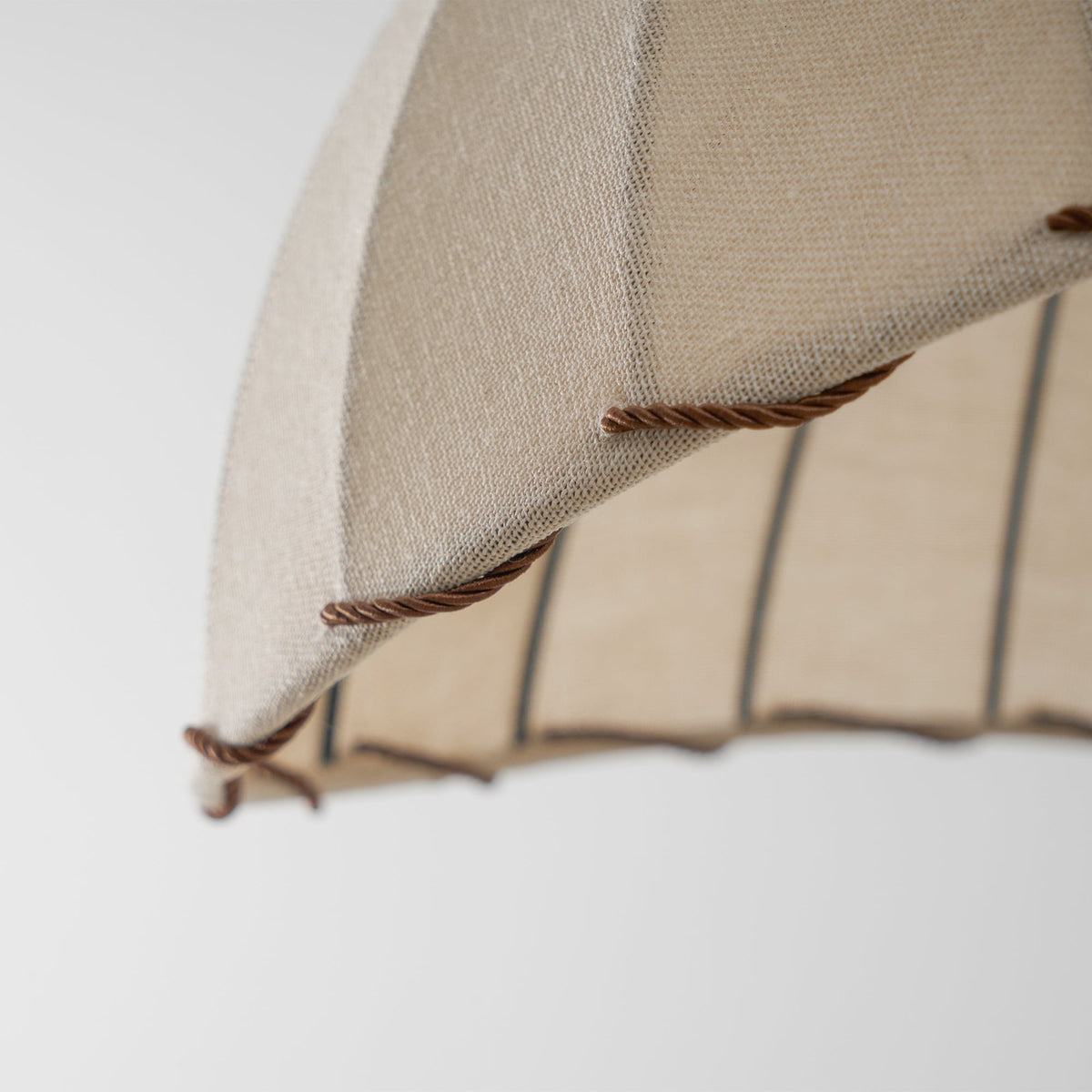 Close view of the braided brown cord stitched along the lower edge of this Clérachic pendant's beige fabric shade.