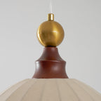 Close view of the brass sphere and turned walnut cap above the beige fabric dome of this Clérachic pendant light.