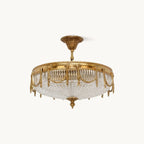 Brass flush-mount ceiling light from Clérachic with a pleated clear glass shade, shown on a plain white backdrop.