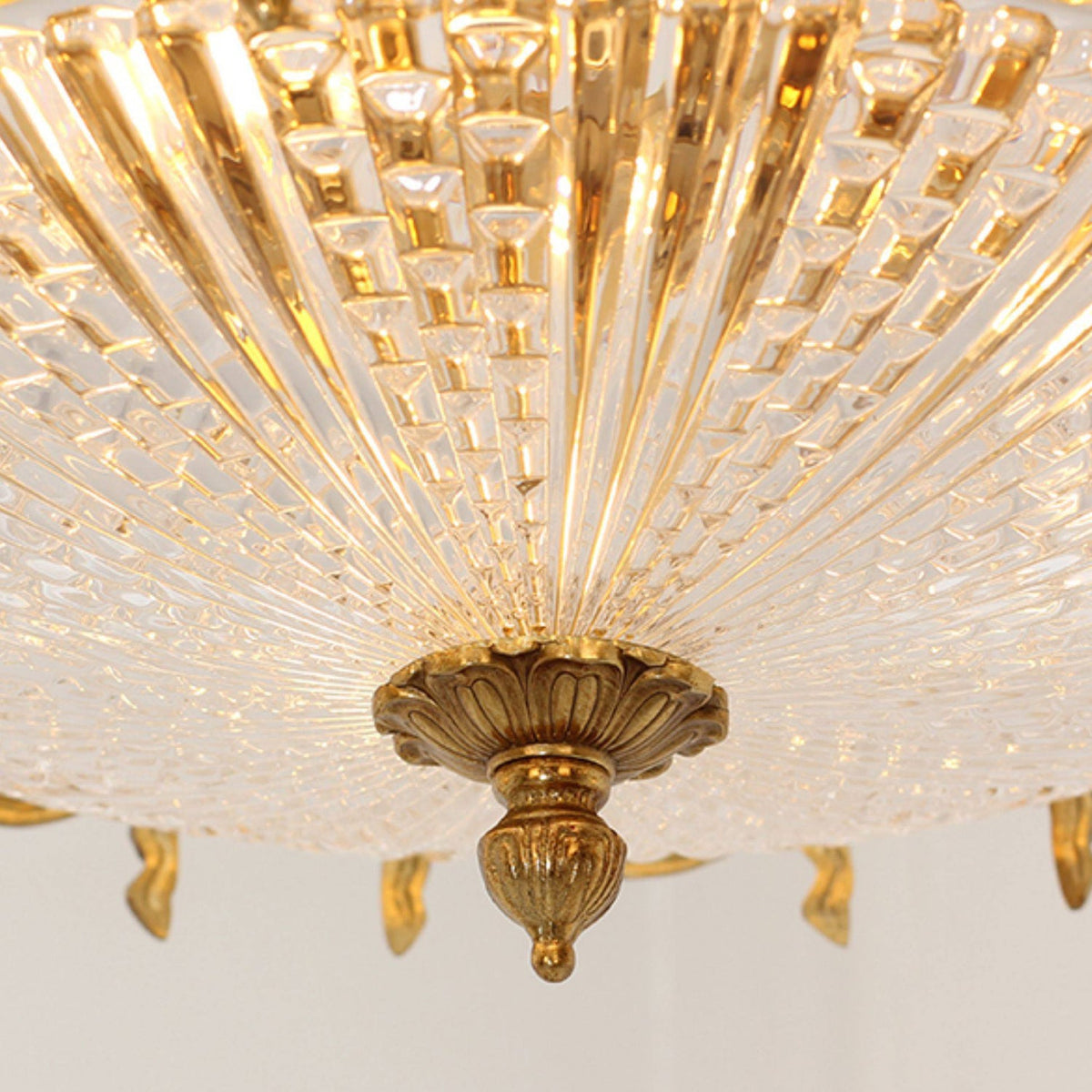 Close view of the radiating glass pleats and the brass finial beneath this Clérachic ceiling light.