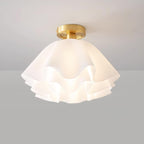 Straight-on studio view of the Clérachic Pleated Petal Ceiling Light lit, the bulb glowing softly through the top layer of petals.