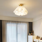 Wide bedroom view with the Clérachic Pleated Petal Ceiling Light glowing above a dressing table set with perfume and flowers.