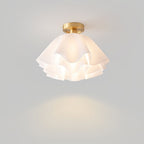 The Clérachic Pleated Petal Ceiling Light switched on against a grey wall, throwing a soft pool of warm light beneath it.