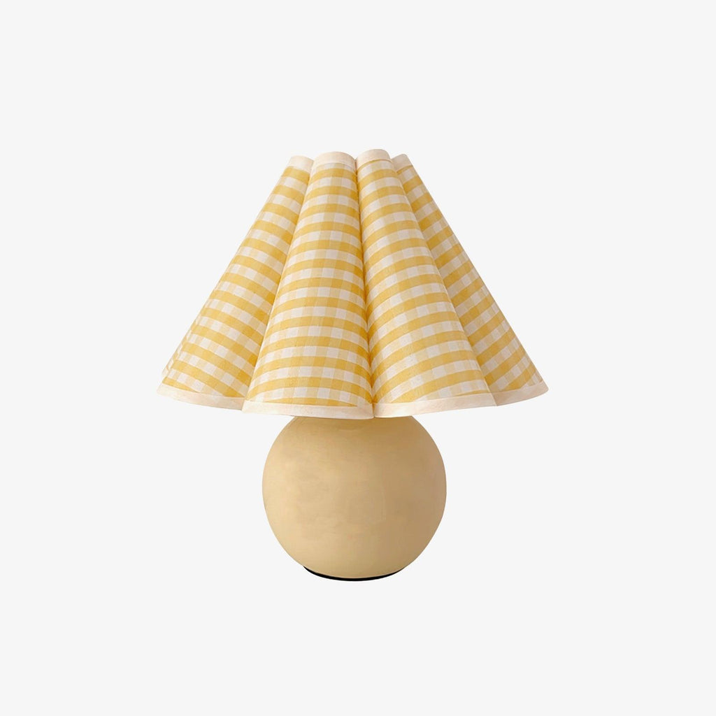 Shown here, a Clérachic table lamp with a yellow plaid pleated shade and a round beige ceramic base, shown on a plain white backdrop.